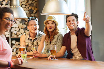 Image showing happy friends with drinks pointing finger at bar