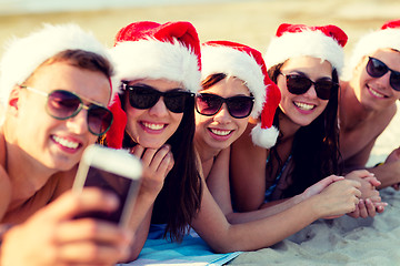 Image showing group of friends in santa hats with smartphone