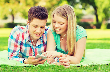 Image showing smiling couple with smartphone and earphones