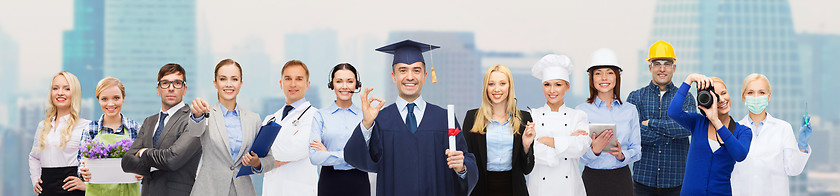 Image showing happy bachelor with diploma over professionals