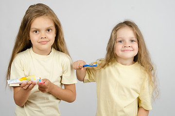 Image showing The girl squeezes out a tube of toothpaste on the brush