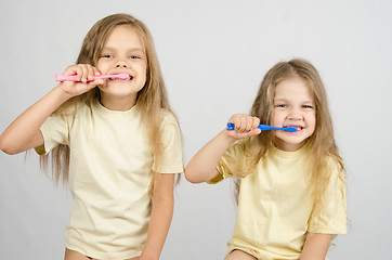 Image showing Two sisters brushing their teeth