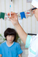 Image showing Doctor pediatrician with a syringe and a child in the background