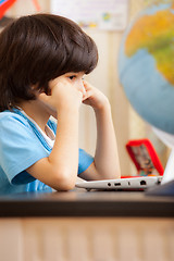 Image showing pensive boy sitting at a table