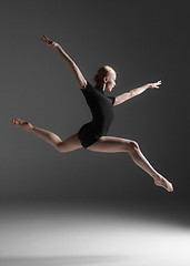 Image showing Young beautiful modern style dancer jumping on a studio background