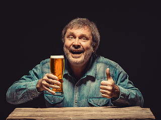 Image showing The smiling man in denim shirt with glass of beer