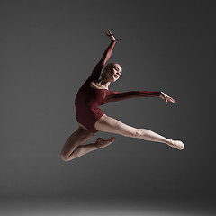 Image showing Young beautiful modern style dancer jumping on a studio background