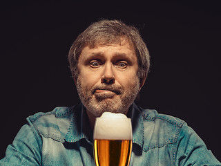 Image showing The spellbound man in denim shirt with glass of beer