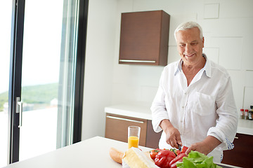 Image showing man cooking at home preparing salad in kitchen