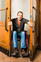 Image showing Man in wheelchair stuck between swing doors