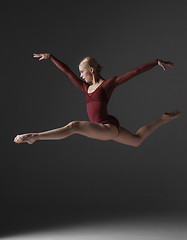 Image showing Young beautiful modern style dancer jumping on a studio background