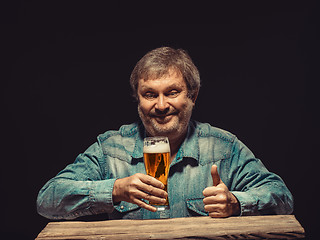 Image showing The smiling man in denim shirt with glass of beer