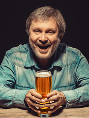 Image showing The smiling man in denim shirt with glass of beer