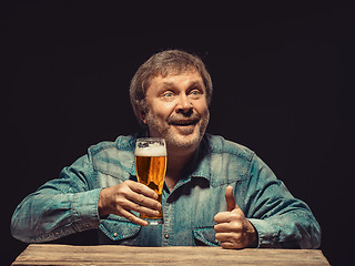 Image showing The smiling man in denim shirt with glass of beer