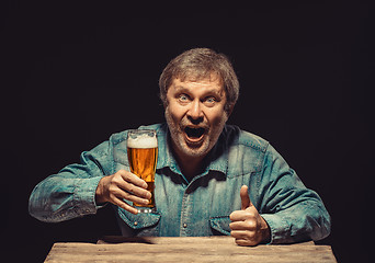 Image showing The smiling man in denim shirt with glass of beer