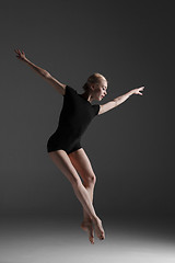 Image showing Young beautiful modern style dancer jumping on a studio background