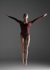 Image showing Young beautiful modern style dancer jumping on a studio background