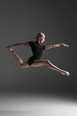 Image showing Young beautiful modern style dancer jumping on a studio background