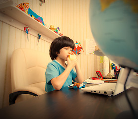 Image showing schoolboy with a laptop eating apple