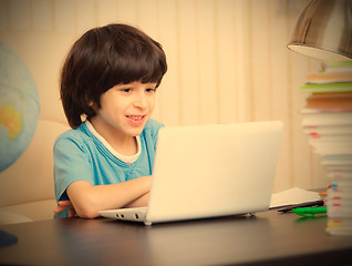 Image showing smiling boy looking at a computer monitor