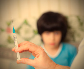 Image showing Doctor pediatrician with a syringe and a child in the background