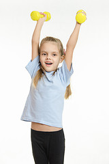 Image showing The girl raised her two dumbbells