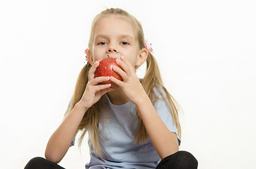 Image showing Six year old girl sitting and eating an apple