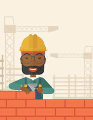 Image showing Black builder man is building a brick wall.