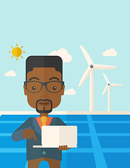 Image showing African man with laptop in solar panel.