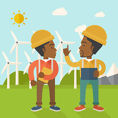 Image showing Two black workers talking infront of windmills.