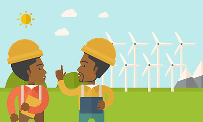 Image showing Two black workers talking infront of windmills.