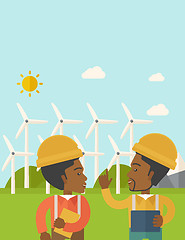 Image showing Two black workers talking infront of windmills.