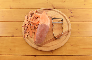 Image showing Sweet potato with vegetable peeler on a chopping board