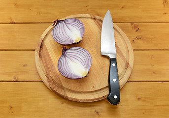Image showing Red onion cut in half with a knife on a cutting board