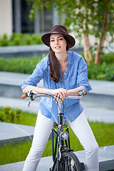 Image showing Pretty girl in hat riding a bicycle at street