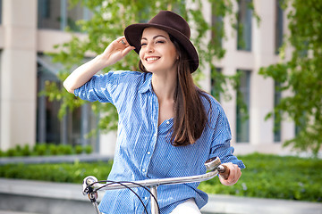 Image showing Pretty girl in hat riding a bicycle at street