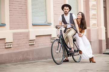 Image showing Young couple sitting on a bicycle against the wall 