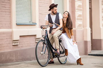 Image showing Young couple sitting on a bicycle against the wall 