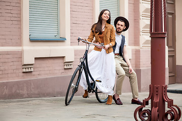 Image showing Young couple sitting on a bicycle against the wall 