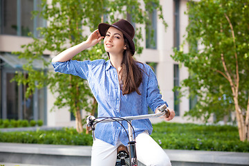 Image showing Pretty girl in hat riding a bicycle at street