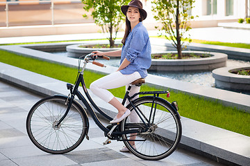 Image showing Pretty girl in hat riding a bicycle at street