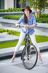 Image showing Pretty girl in hat riding a bicycle at street