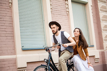 Image showing Young couple sitting on a bicycle against the wall 