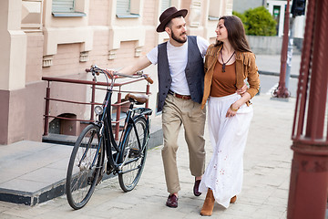 Image showing Young couple walking with bicycle and hugging
