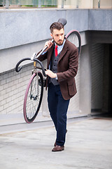 Image showing Handsome businessman carrying his bicycle