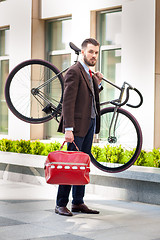 Image showing Handsome businessman carrying his bicycle in office