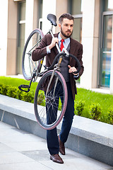 Image showing Handsome businessman carrying his bicycle