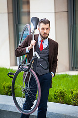 Image showing Handsome businessman carrying his bicycle