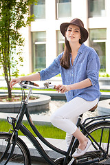 Image showing Pretty girl in hat riding a bicycle at street