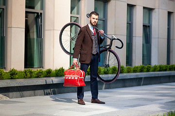 Image showing Handsome businessman carrying his bicycle in office